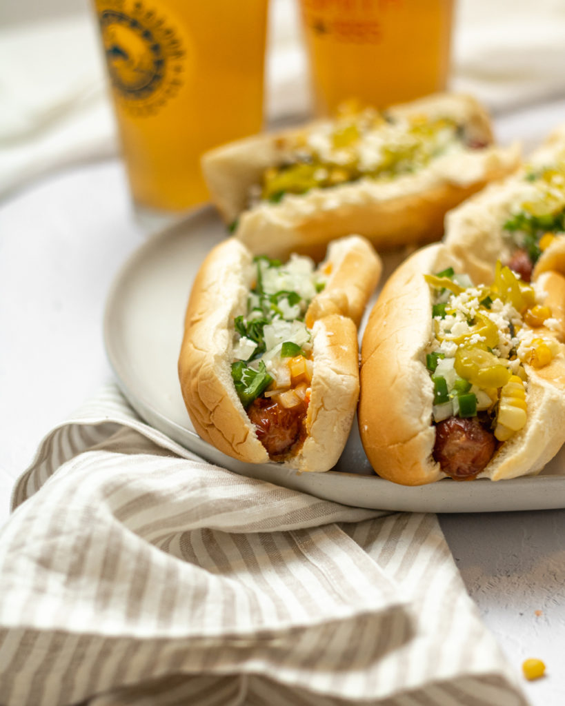 a plate of Mexican hot dogs and a couple of beers